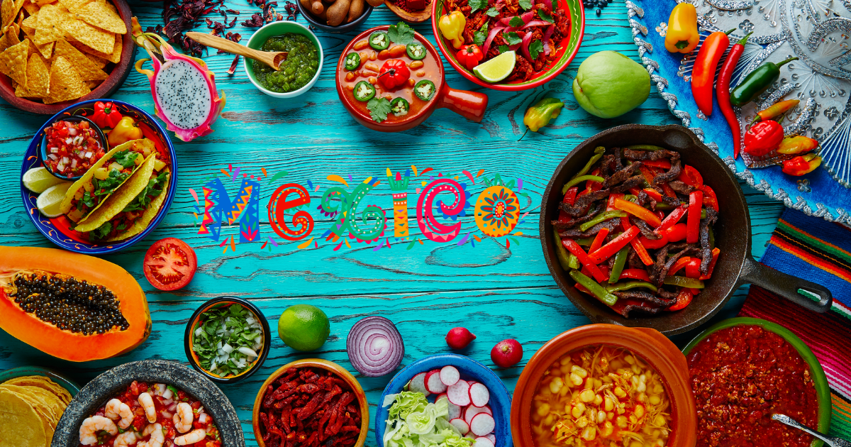 A colorful spread of Mexican cuisine, including tacos, chili con carne, fajitas, guacamole, salsa, and other traditional dishes, arranged on a blue wooden background with the word "Mexico" spelled out in colorful letters.