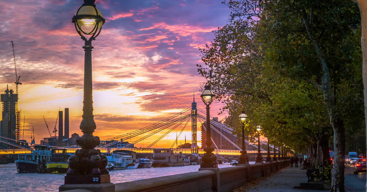 A beautiful sunset over the River Thames in London, with a bridge and lampposts in the foreground.