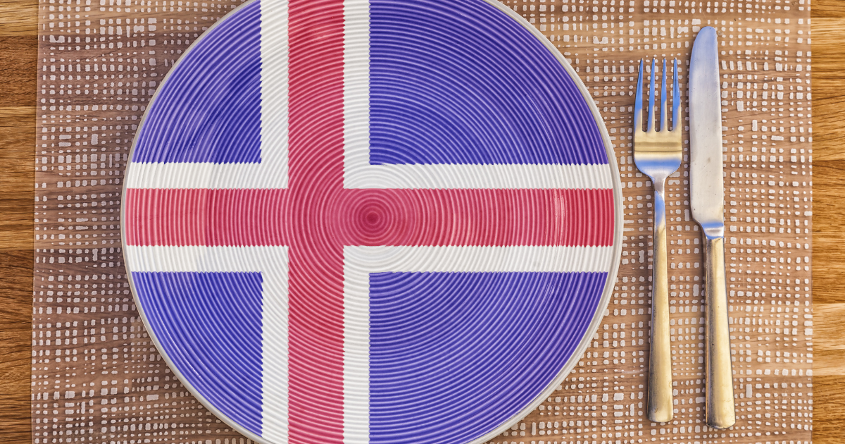 The Icelandic flag painted on a plate, with a fork and knife beside it.