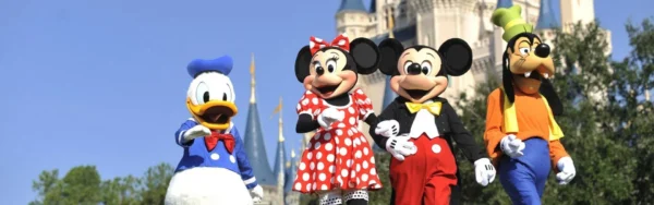 Mickey Mouse, Minnie Mouse, Donald Duck, and Goofy in their iconic costumes, in front of Cinderella's Castle.