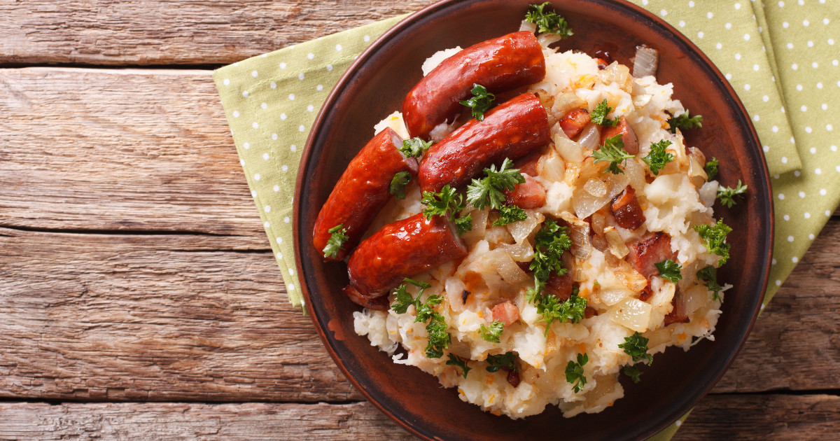 Dutch winter meal stamppot of potatoes, cabbage and carrots, with sausages close up on a plate. .jpg