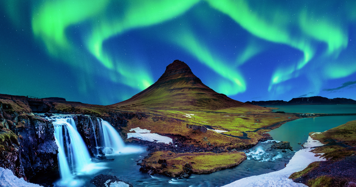 A breathtaking view of the Northern Lights illuminating the night sky above Kirkjufell mountain and a cascading waterfall in Iceland.