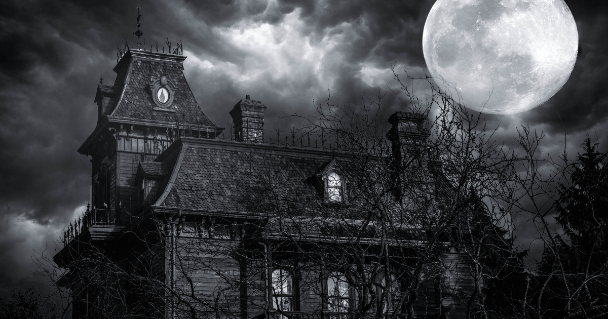 A creepy, old house with a full moon in a stormy sky, surrounded by bare trees.