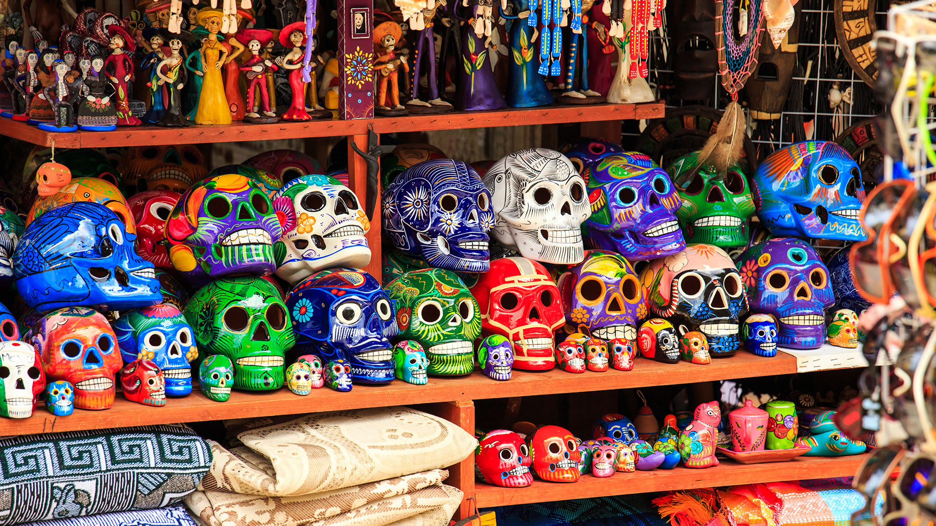 A vibrant display of colorful sugar skulls, or calaveras, a traditional symbol of Día de los Muertos, on a market stall in Mexico.