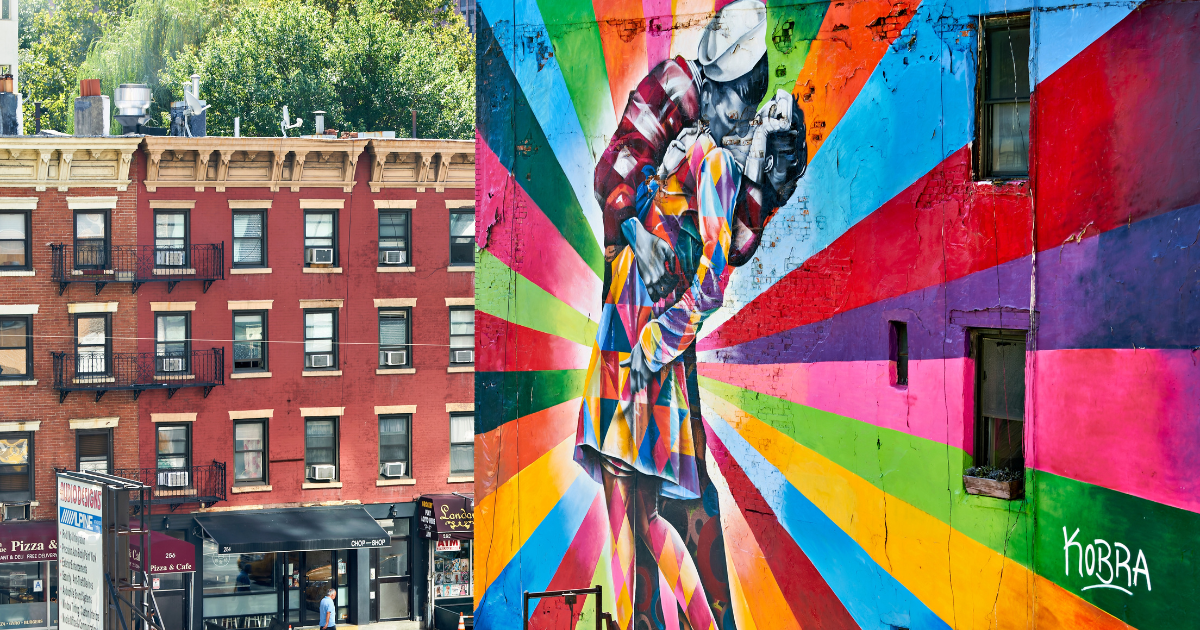 A vibrant mural of a sailor kissing a nurse, inspired by the iconic "V-J Day in Times Square" photograph, painted on the side of a building in New York City.