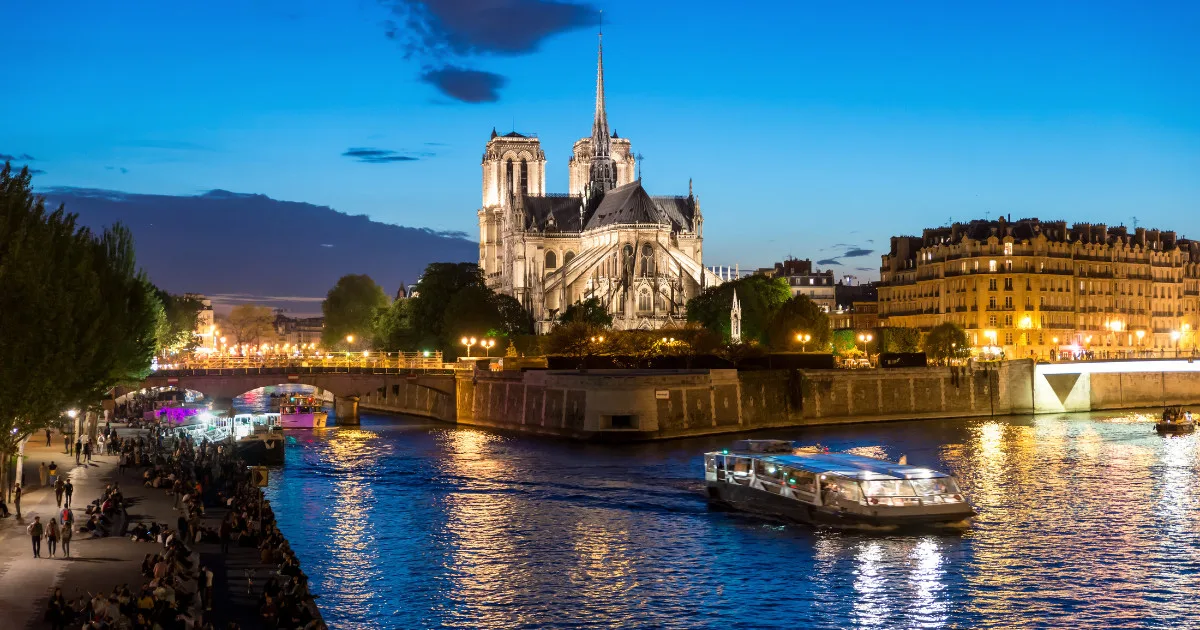 Notre Dame de Paris with cruise ship on Seine river at night in Paris, France. Landscape and Landmarks travel, or historical building and sightseeing in Europe concept