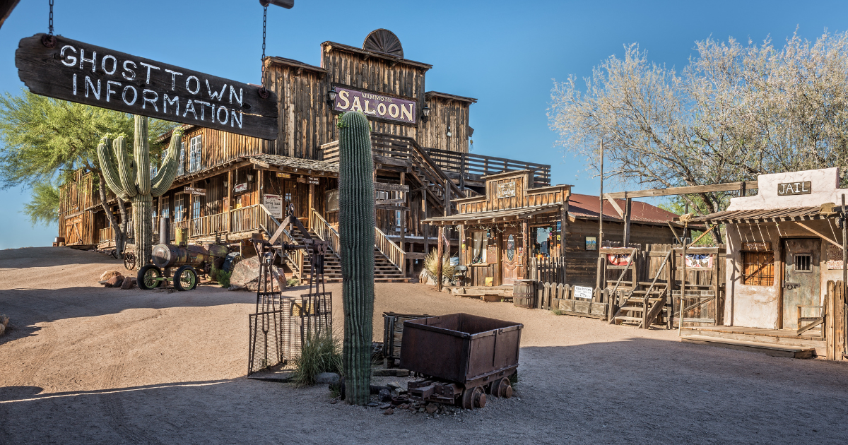 A view of the restored buildings in Goldfield Ghost Town, Arizona, including the "Ghost Town Information" sign, a saloon, and a jail.