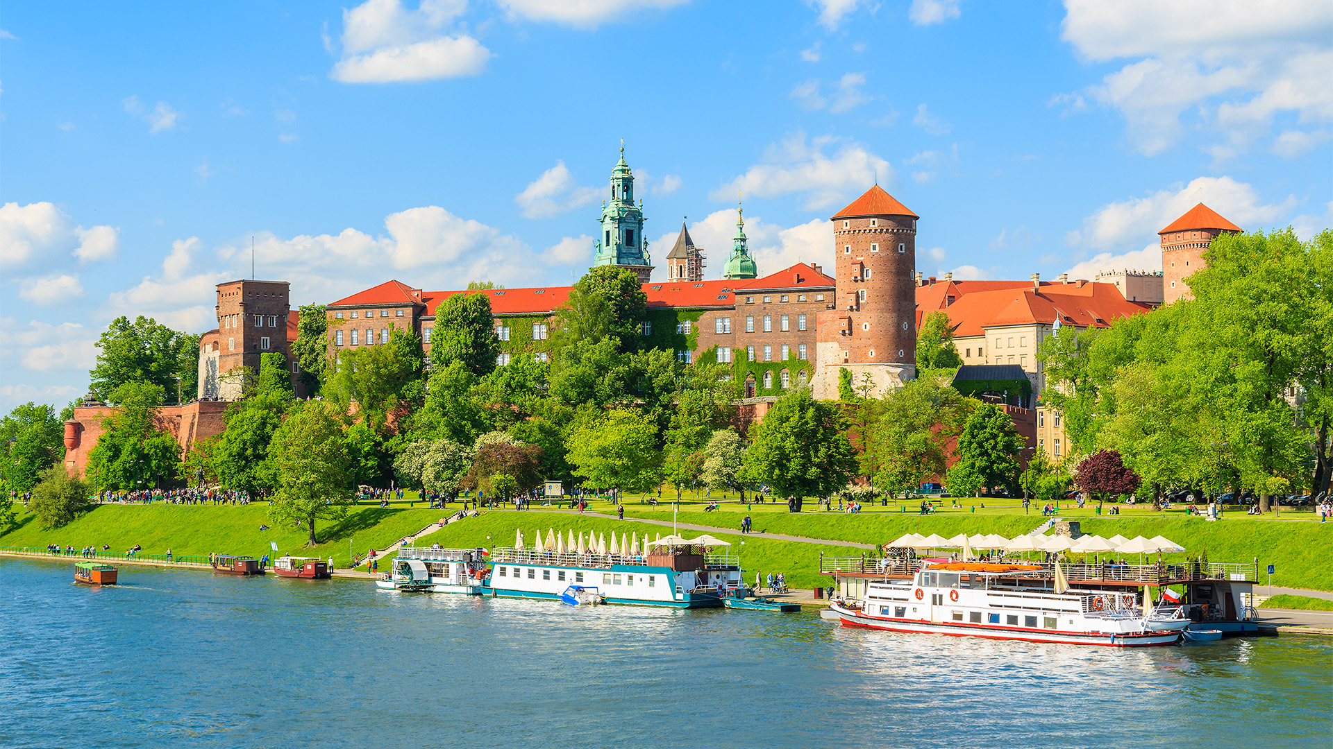 A fasinating view of Wawel Castle in Krakow, Poland, with its red-tiled roofs and towers, overlooking the Vistula River.