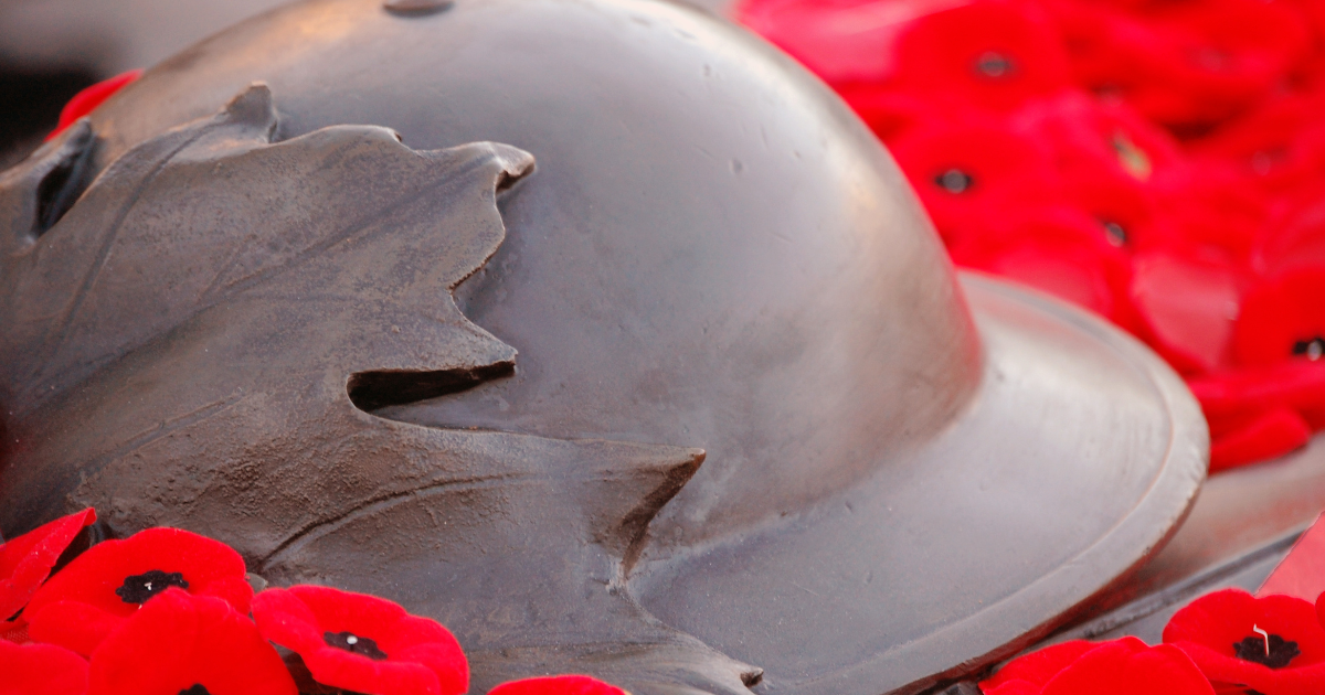 A Canadian military helmet with a maple leaf emblem, surrounded by red poppies, symbolizing Remembrance Day.