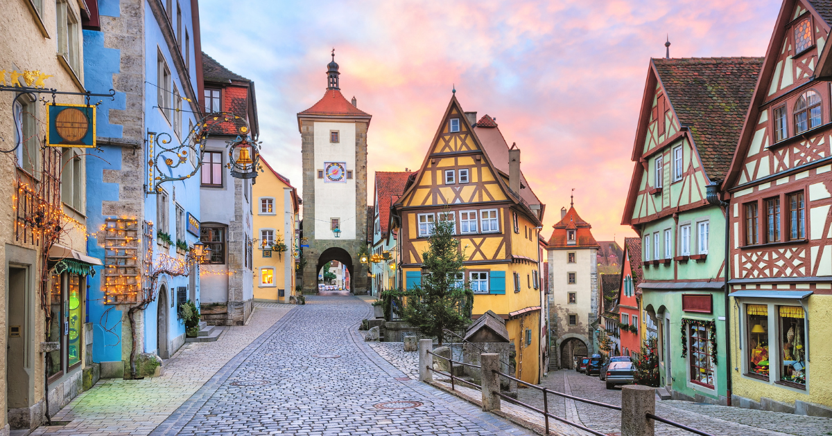 A picturesque street in Rothenburg ob der Tauber, Germany, with colorful half-timbered houses and a historic gate.