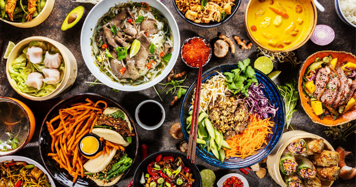 A vibrant assortment of Thai cuisine, featuring dishes like pho, ramen, dumplings, spring rolls, and various stir-fries.