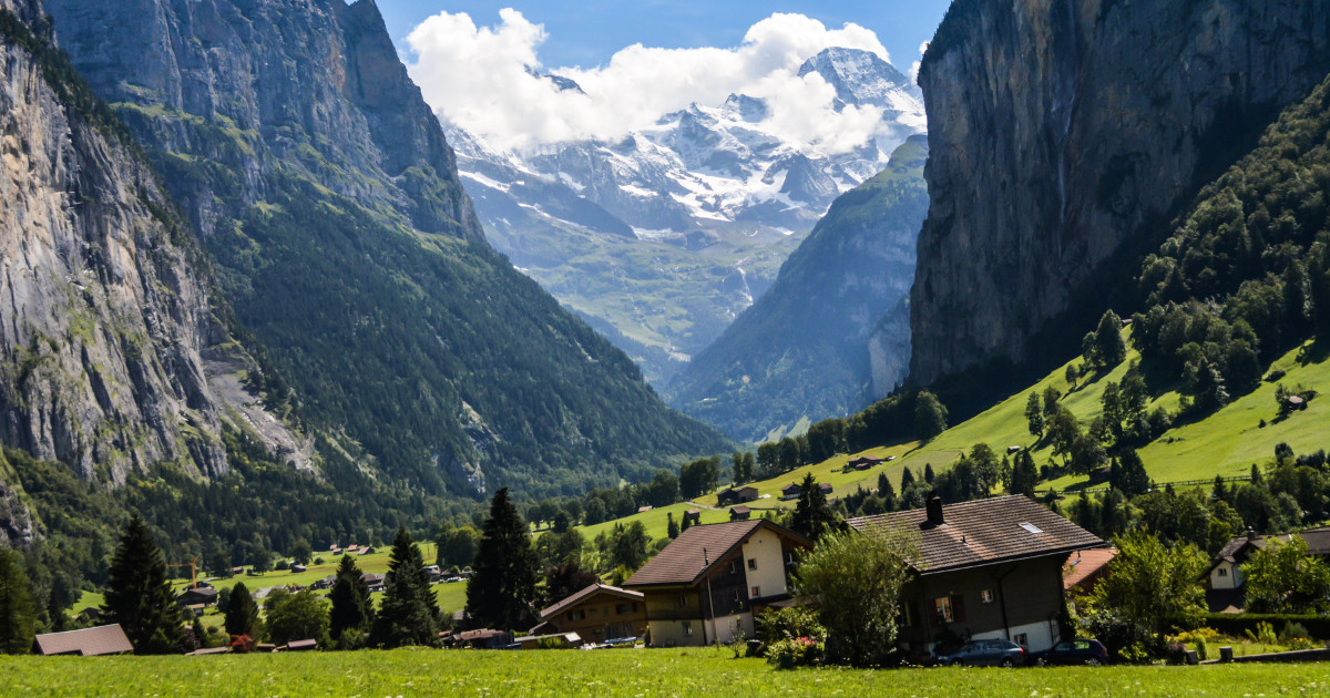 Lauterbrunnen Valley in Switzerland, with towering cliffs, lush green meadows, and charming houses.