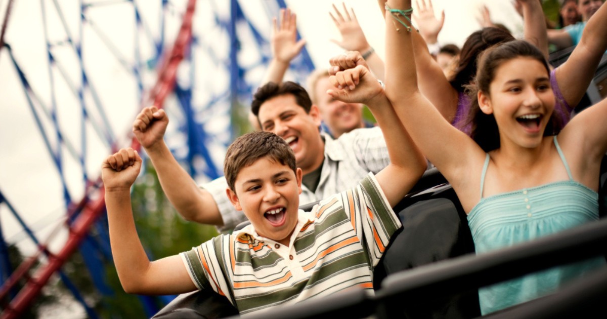 Smiling family riding on a rollercoaster at an amusement park