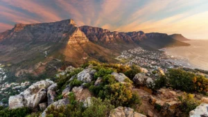 A panoramic view of Table Mountain and the city of Cape Town, with a dramatic sunset sky.