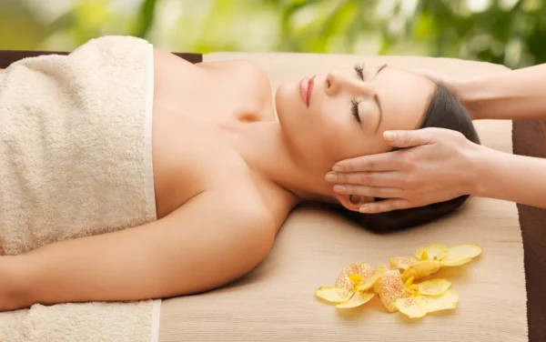 a woman receiving a massage from a therapist. The woman appears to be in a relaxing and serene environment surrounded by nature.