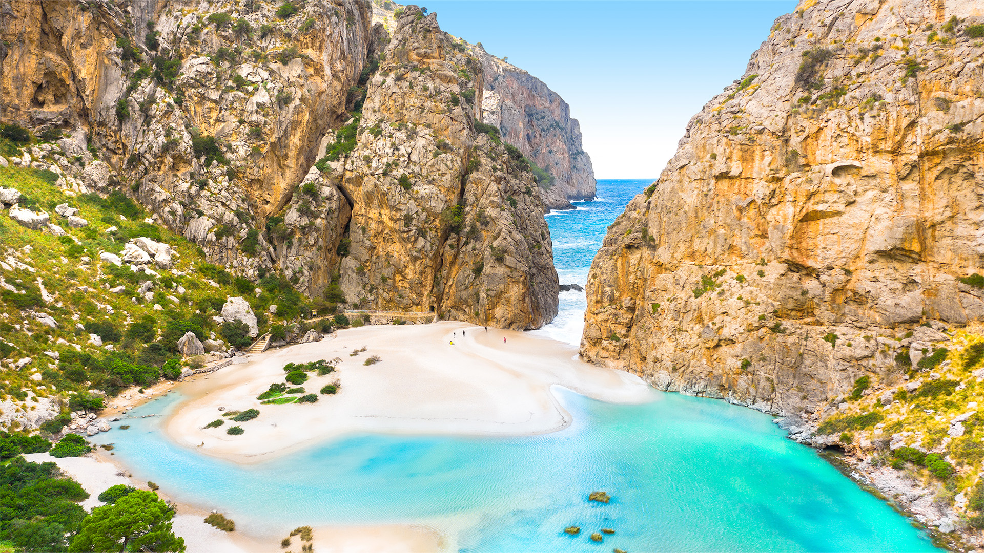 A breathtaking view of Cala Macarella, a secluded beach in Menorca, Spain, surrounded by dramatic cliffs and crystal-clear turquoise water.