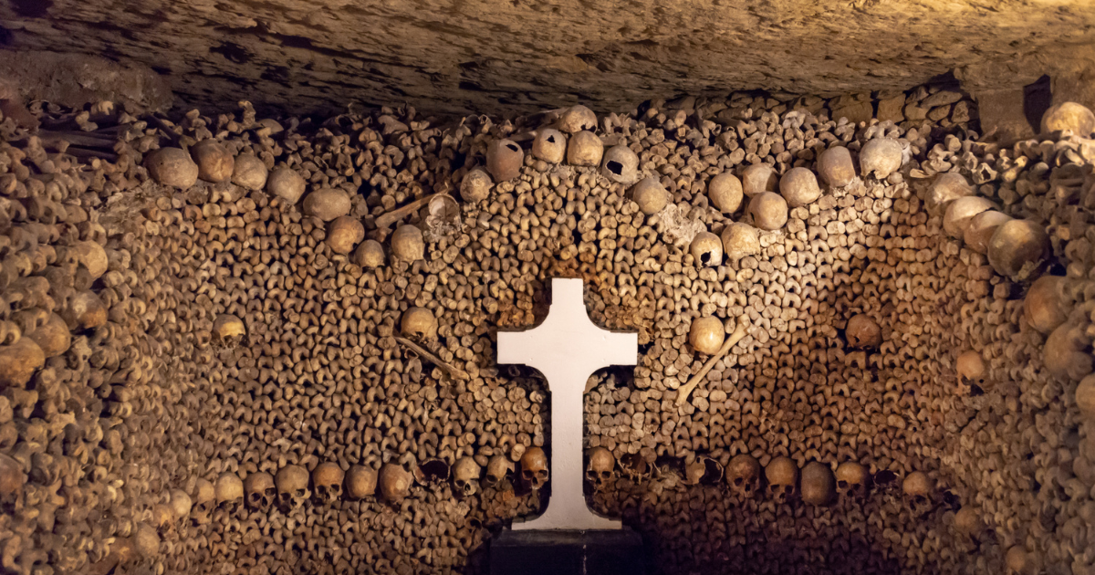 A cross surrounded by human skulls and bones in the Catacombs of Paris.