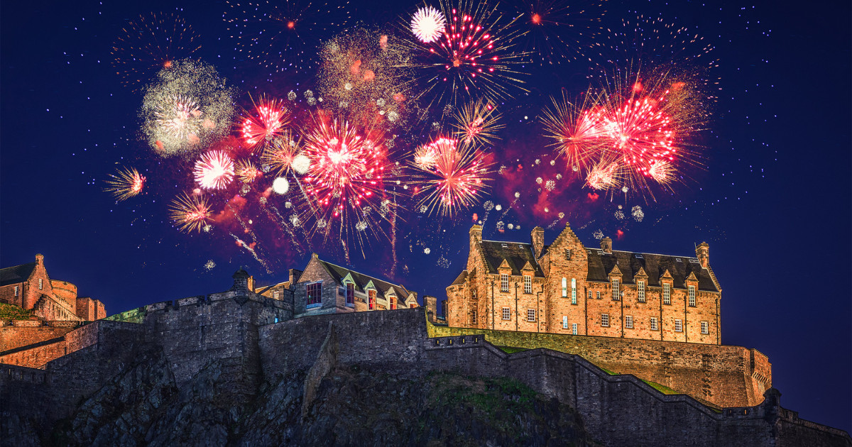 A vibrant display of fireworks illuminating the night sky over Edinburgh Castle during Hogmanay celebrations.