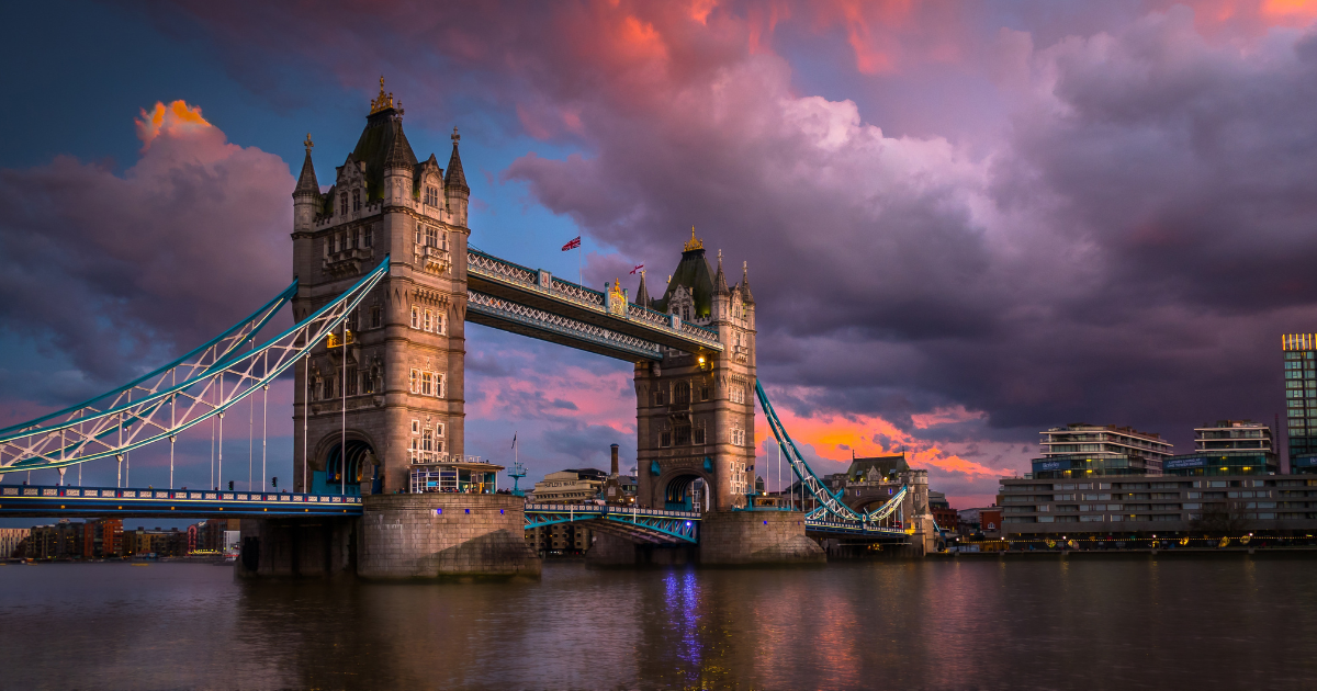 The majestic Tower Bridge, with its distinctive bascules raised, illuminated against a dramatic sunset sky.