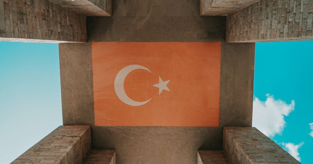 The Turkish flag painted on the ceiling of a monument, with a blue sky visible through the structure.