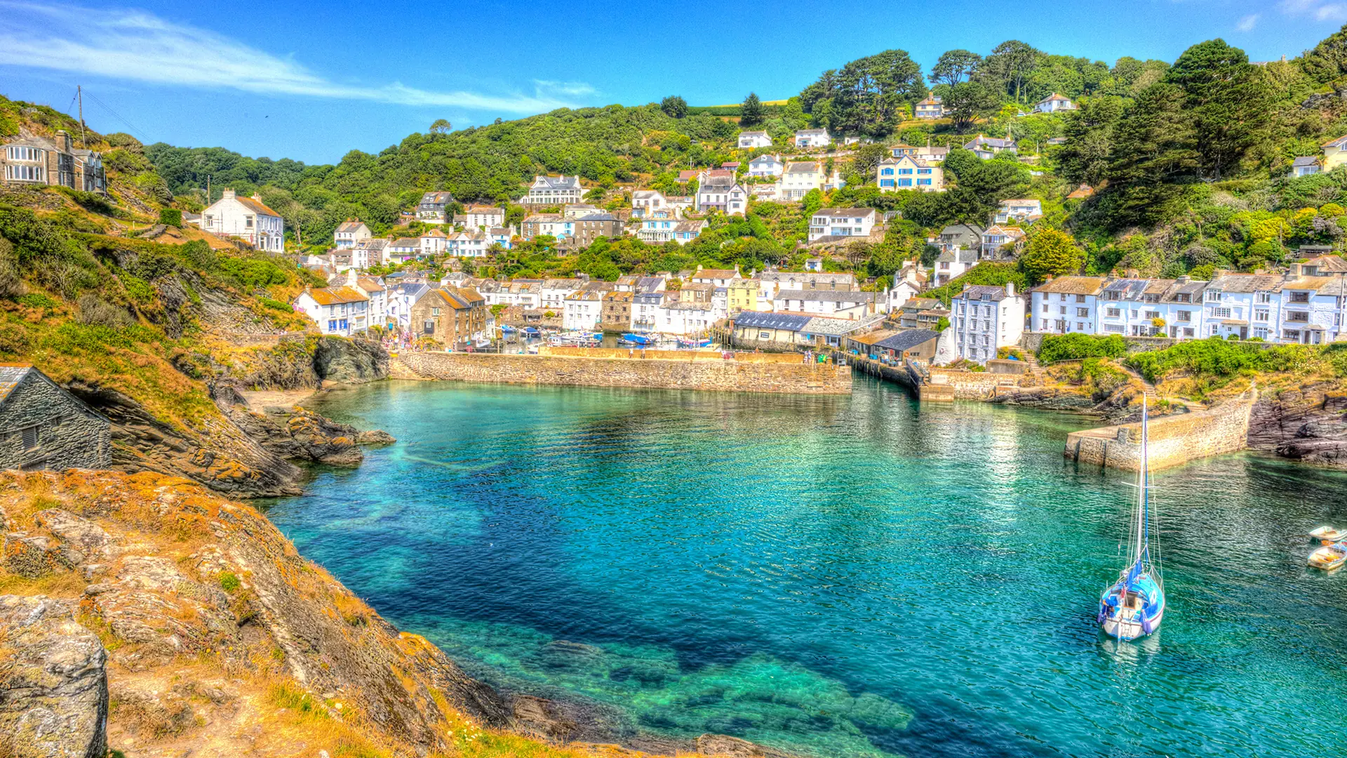 A vibrant view of Polperro, a charming fishing village in Cornwall, England, with colorful houses, a bustling harbor, and crystal-clear waters.