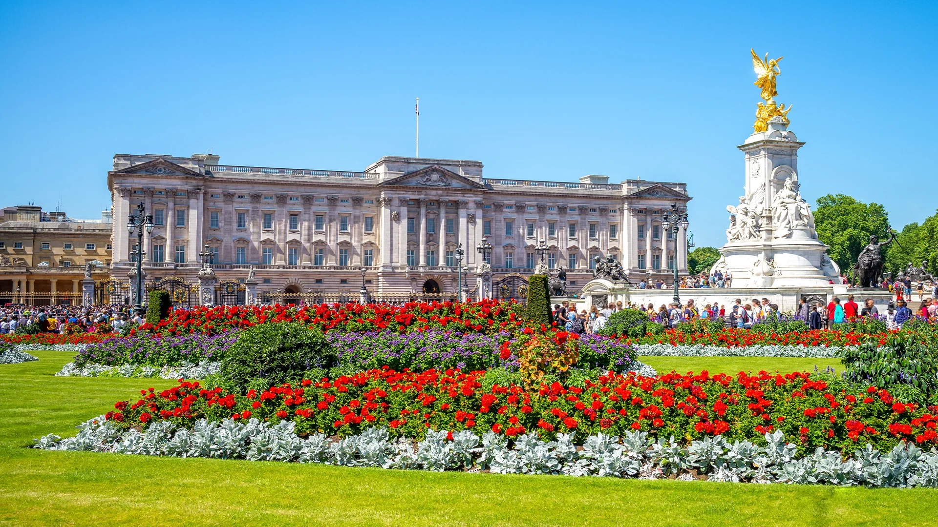 Buckingham Palace and the Victoria Memorial in London, with a beautiful garden in the foreground.