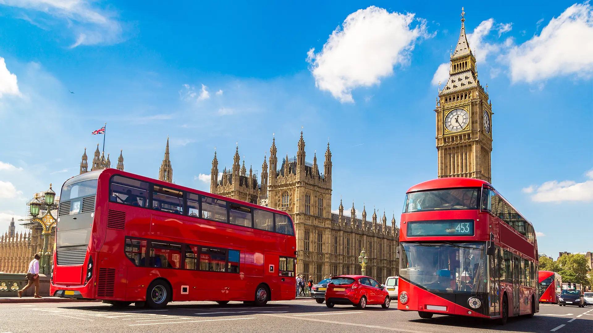 A view of Big Ben and Houses of Parliament with red double-decker buses in London.