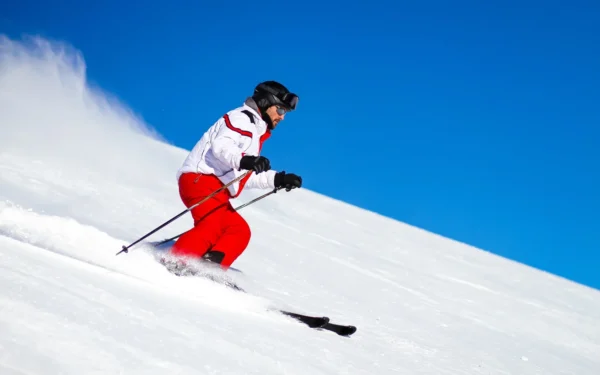 A person skiing down a snowy slope against a clear blue sky.