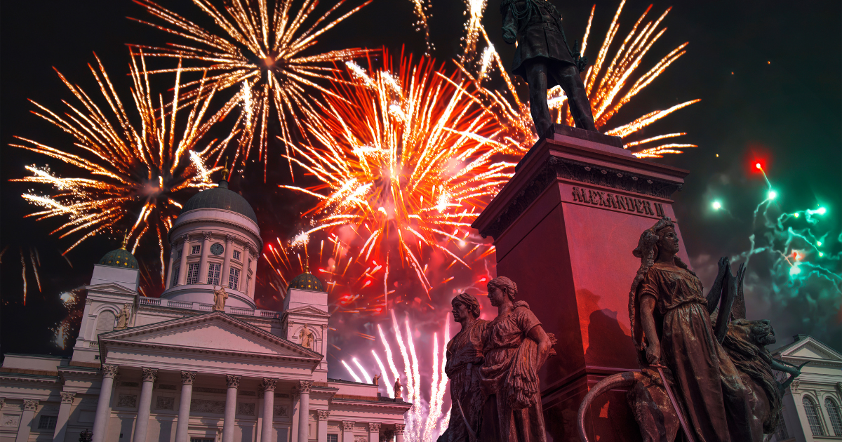 A stunning fireworks display illuminating the night sky above Senate Square in Helsinki, with the Helsinki Cathedral and statues in the foreground.